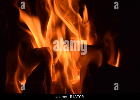 Close up di mattonelle di lignite sul fuoco con rosso giallo dentro le fiamme di un solido speciale forno, rosso e arancione texture sfocate su uno sfondo nero. Foto Stock