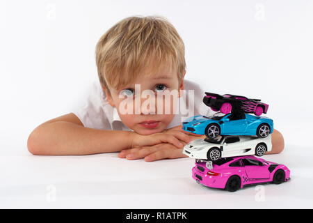 Bambino ragazzo giocando con automobili giocattolo in uno studio, la costruzione di una torre Foto Stock