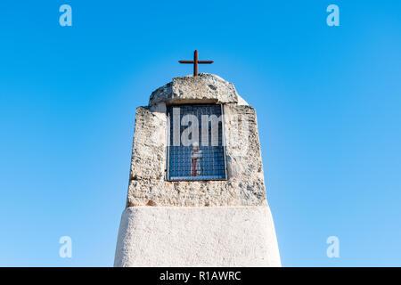 Primo piano di un oratorio con una croce di metallo e una statuetta religiosa all'interno, adagiato su un cielo azzurro limpido in Provenza, nel sud della Francia, sacro santuario Foto Stock