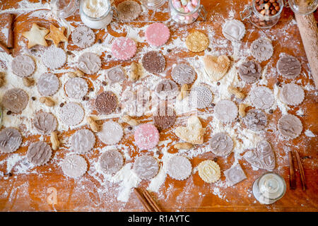 Diversi tipi di cookie su una tavola di legno decorato tabella coperta di farina cotta al forno. Impasto arrotolato con un pattern e il cookie di varie forme. Biscuit cooki Foto Stock