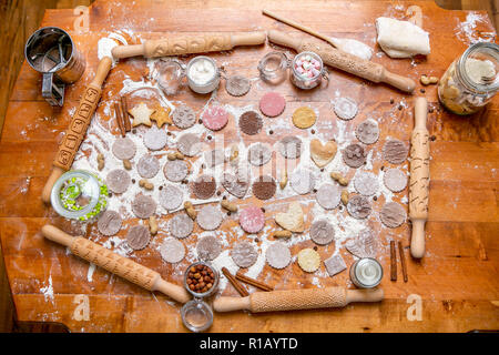 Diversi tipi di mattarello e cookie in un legno decorato tabella coperta di farina cotta al forno. Impasto arrotolato con un pattern e il cookie di varia forma Foto Stock