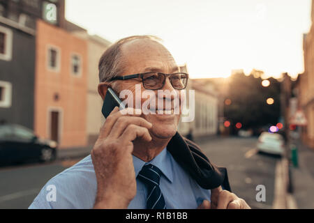 Ravvicinata di un imprenditore senior parlando su telefono cellulare. Imprenditore matura una telefonata mentre in piedi all'aperto nella strada della citta'. Foto Stock