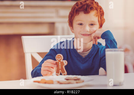 Carino boy in posa tenendo gingerbread man Foto Stock