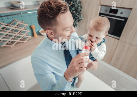 Attenzione uomo sorridente permanente e la alimentazione di un bambino. Foto Stock