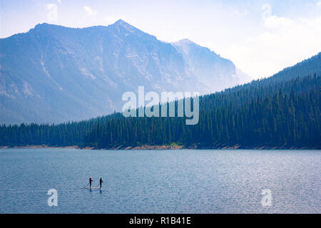 Lago di montagna di ricreazione. Paddle boarders drift attraverso il serbatoio Hyalite nel Montana. Rilassante vacanza all'aperto in scena con la maestosa copia spazio. Foto Stock