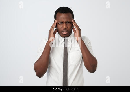 Nero Africa Uomo in camicia bianca che mostra quanto il suo mal di testa, dolore, cercando di miserabili e esaurito Foto Stock