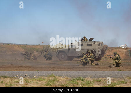 Formazione KADAMOVSKIY MASSA, ROSTOV REGIONE, Russia, 26 AGOSTO 2018: drappello di soldati armati insieme con un auto blindata sul campo di battaglia di difendere il Foto Stock