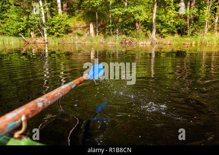 Vista dettagliata del remo pala dalla riga barca in movimento in acqua sul lago verde con increspature. Campeggio turismo viaggio relax uno stile di vita attivo adventure concept Foto Stock