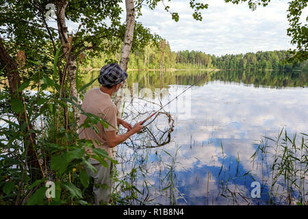 Pescatore con canne da pesca è la pesca sullo sfondo della splendida natura e lago o fiume. Campeggio turismo viaggio relax uno stile di vita attivo avventura Foto Stock