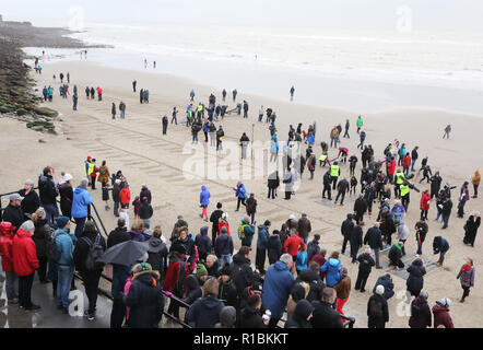 Folkestone, Kent, Regno Unito. Xi Nov, 2018. I membri del pubblico hanno aderito in usando stampini per fare 100 delinea delle vite perse in guerre, a Folkestone, Kent, nel novembre 11th, 2018, segnando l'Armistizio Centenario Credito: Monica pozzetti/Alamy Live News Foto Stock