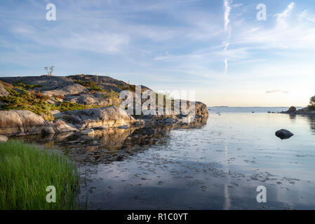 Rocce e alberi riflessa sul tramonto. Finlandia arcipelago. Foto Stock