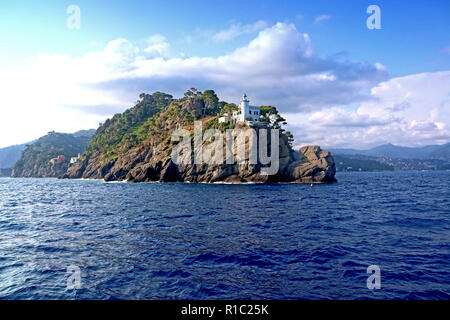 Vista dalle acque blu del mar ligure del faro di Portofino sulla penisola che chiude il golfo Foto Stock