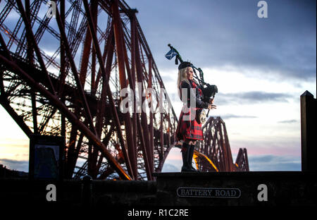 Piper Louise Marshall, indossando una speciale commemorativa tartan rosso, riproduce della battaglia O'er, la musica tradizionale scozzese lamento svolto alla fine della battaglia, all'alba a fianco del Ponte di Forth a North Queensferry sul centesimo anniversario della firma dell'armistizio che ha segnato la fine della Prima Guerra Mondiale. Foto Stock