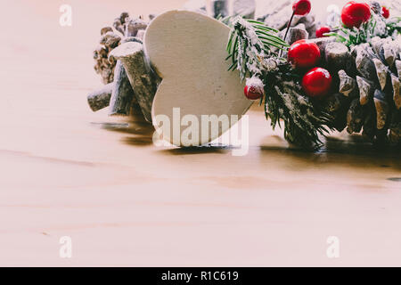 Scandinavian ghirlanda di Natale con bacche rosse e pigne sulla luce di un tavolo di legno Foto Stock