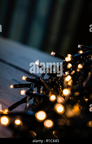 Favola di natale luci avvolto intorno alla scheda su una tavola di legno di notte Foto Stock