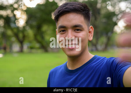 Bel giovane uomo asiatico tenendo selfie con telefono mobile Foto Stock