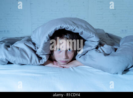 Grazioso piccolo ragazza caucasica giacenti nel letto che copre la sua testa con coperta sensazione di esaurimento e insonne che soffrono di insonnia Depressione Stress in ch Foto Stock