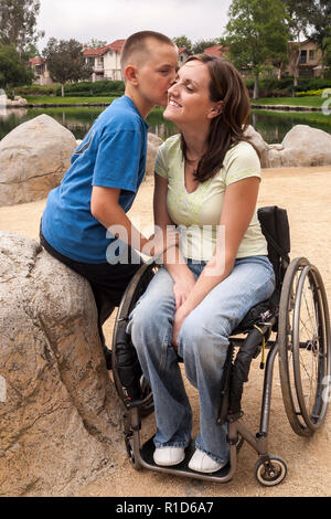 Figlio di baciare la guancia della madre disabili in carrozzella © Myrleen Pearson ...Ferguson Cate Foto Stock