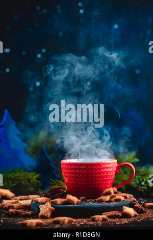 Natale bevanda calda con vapore ascendente, cannella e a forma di stella i cookie. Grande tazza di caffè con fatti in casa a base di cacao. Inverno bere la fotografia al buio su un bac Foto Stock