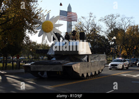 Novembre 11, 2018 - Washington, DC, Stati Uniti - un finto serbatoio con un gigante di fiori artificiali nella sua torretta mitragliatrice e qualcuno tenendo in mano una bandiera americana essendo pilotati attraverso Washington, DC il giorno dei veterani. Il serbatoio è mostrato sulla 17th Street NW Near E Street essendo seguita da una macchina della polizia. Il Monumento di Washington può essere visto in background. (Credito Immagine: © Evan Golub/ZUMA filo) Foto Stock