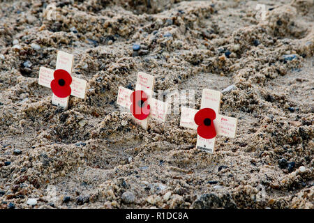 Gorleston-On-Mare, Norfolk. 11 novembre 2018. Tre croci baring papaveri collocato nella sabbia sulla spiaggia Gorleston, mettendo i nomi di alcuni dei caduti della Prima Guerra Mondiale 100 anni dopo la fine del conflitto. Credito: Adrian Buck/Alamy Live News Foto Stock