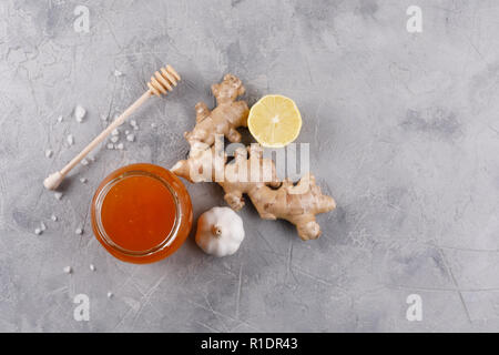 Il miele in un vasetto di vetro e miele stick. Anti-kit freddo con l'aglio e lo zenzero in polvere e il succo di limone. Vista da sopra. Foto Stock