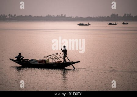 I pescatori e barche stagliano contro la luce della sera nel Subarbans, West Bengal, India Foto Stock