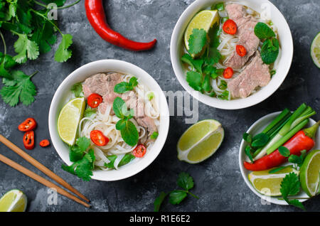 Tradizionale zuppa vietnamita Pho Bo con spaghetti di riso, carne di manzo e di erbe su sfondo scuro, Cucina Asiatica Foto Stock