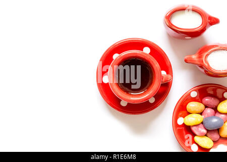 Il tè del caffè in tazza rossa con una tazza di latte e zucchero e caramelle isolati su sfondo bianco. Vista dall'alto. Foto Stock