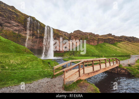 Cascata Seljalandfoss al tramonto. Ponte sul fiume. Natura fantastica. L'Islanda. Foto Stock