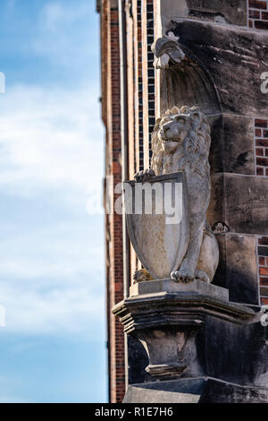 Araldico scolpito in pietra lion statua con protezione su un plinto sull'angolo di uno storico edificio in mattoni. Foto Stock