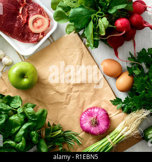 Il telaio dal sacchetto di carta e impostare il cibo sano su bianco tavolo in legno. Vista dall'alto. Lay piatto. Concetto acquistare cibo sano Foto Stock