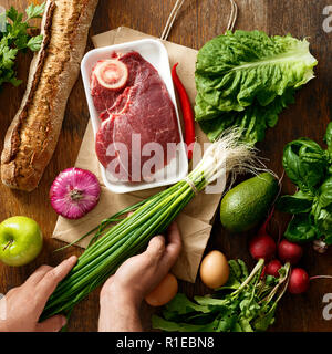 Vista dall'alto sacchetto di carta con una varietà della salute alimentare sul tavolo di legno. Vista dall'alto. Lay piatto Foto Stock