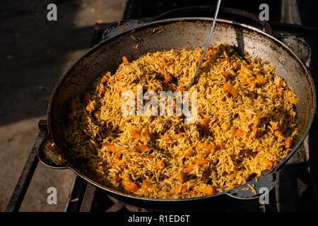 Gustosa Uzbek pilaf in un paiolo di rame all'aria aperta a street food festival Foto Stock