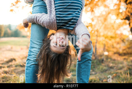 Un padre che tiene una piccola figlia capovolto in autunno la natura. Foto Stock