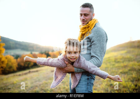 Un giovane padre avendo divertimento con una piccola figlia in autunno la natura. Foto Stock