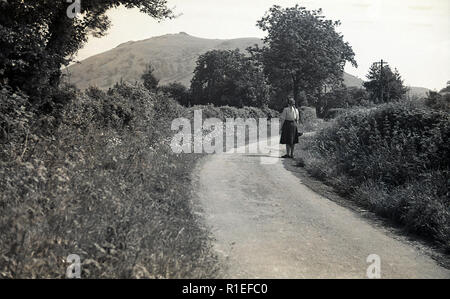 Degli anni Cinquanta, storico Exmoor, Inghilterra, e a una signora walker in piedi su un percorso in campagna. Foto Stock