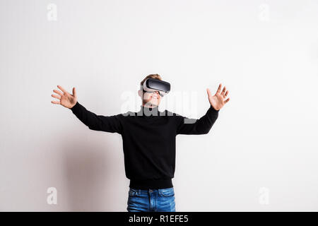 Ritratto di un giovane uomo con la realtà virtuale gli occhiali di protezione in un studio. Foto Stock