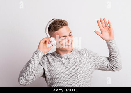 Ritratto di un felice giovane con le cuffie in un studio. Foto Stock