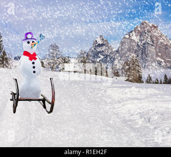 Auguri di Buon Natale una divertente festa pupazzo di neve slitta verso il basso di una collina di sci pendenza su una slitta in caso di neve Foto Stock