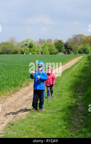 Due bambini piccoli, 7 e 3, esplorando su un sentiero in una fredda giornata di primavera. Foto Stock