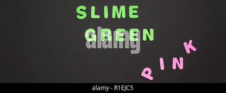 Creative testo colorato in plastica lettere Slime scritta Verde su nero lo sfondo della carta con copia spazio. Colore alla moda concetto blogger template Foto Stock