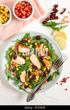 Insalata con salmone alla griglia, rucola, mais, melograno e mirtillo palustre cosparso con limone e olio di oliva. Foto Stock