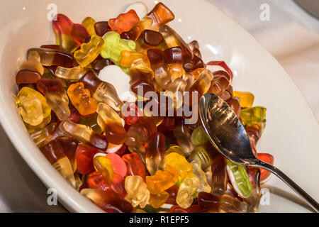 Gummi Cola bottiglie caramelle in una ciotola bianco pronto con un cucchiaio su di esse a una festa per bambini Foto Stock