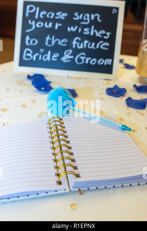 Scrivere il vostro desiderio la sposa e lo sposo o un delizioso coppie in viaggio di nozze con un colorato penna blu. Segno su una visita a libro. Futura sposa e lo sposo. Foto Stock