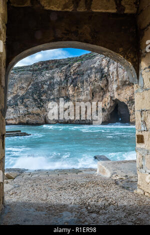 In un luminoso giorno d'inverno con mare mosso in Dwejra Inland Sea. Grotta che collega questa piccola baia al Mediterraneo esterno acqua pulita. Copia Foto Stock