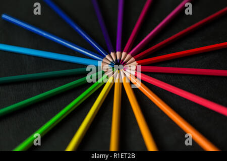 Luminose matite colorate su gesso nero board close-up Foto Stock
