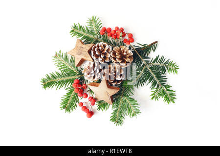 Christmas Festive composizione in stile. Inverno composizioni floreali. Coni di pino, abete rami, rosso rowan bacche e stelle di legno e sul tavolo bianco Foto Stock