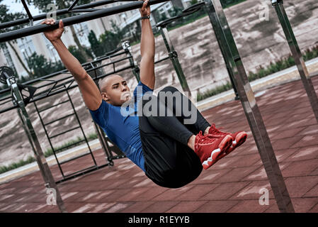 L'uomo africano sta facendo esercizi di stretching in palestra a cielo aperto nei pressi del parco Foto Stock