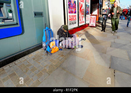 Uomo senza tetto con un cane, la lettura di un libro, The Strand, Londra, Inghilterra, Regno Unito. Foto Stock